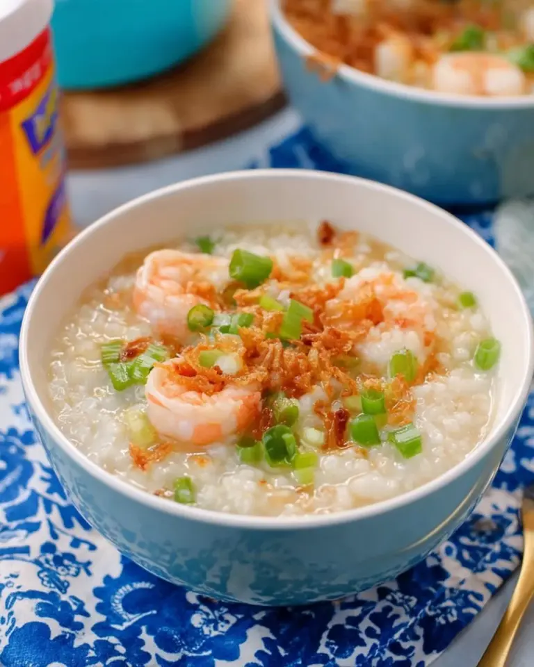 Bowl of Thai breakfast rice soup with shrimp, garnished with herbs