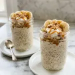 Banana cream pie protein overnight oats topped with fresh bananas and whipped cream.